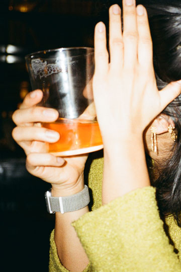 Frau mit Drink hält Hand vors Gesicht