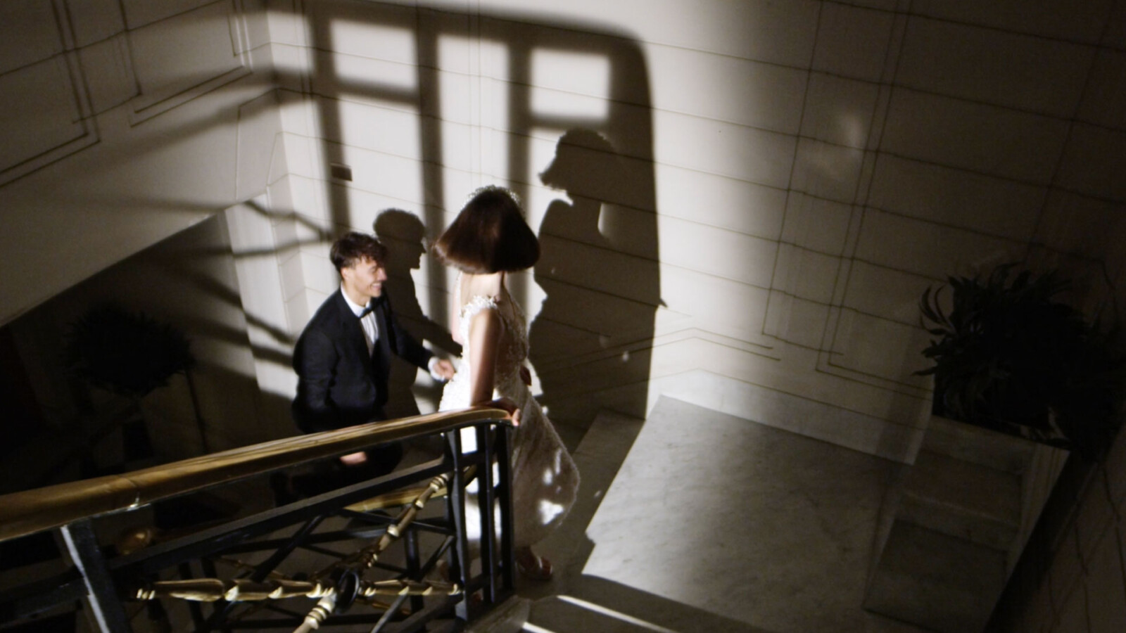 Braut im weissen Kleid und Bräutigam rennen glücklich eine Treppe hinauf.
